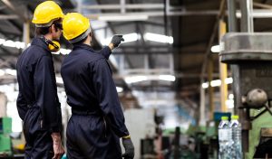 Man at work. Mechanical Engineer man in Hard Hat Wearing Safety Jacket working in Heavy Industry Manufacturing Facility. Professional Engineer Operating lathe Machinery