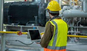 Technician using a laptop computer working at a water treatment plant.