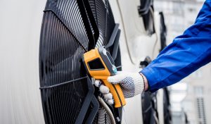 Technician uses a thermal imaging infrared thermometer to check the condensing unit heat exchanger