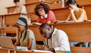 Multiethnic group of students sitting at lecture at Technical College and doing task