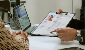 Header of Man Interviewing Young Adult Man Reviewing Resume in Office