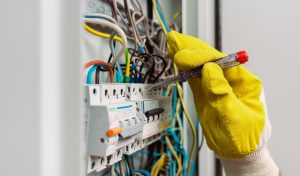 Selective focus of electrician using screwdriver while fixing electric panel