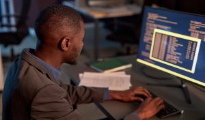 High angle view at black IT developer wearing suit and using computer while working on data security project in office