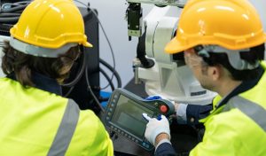 Two male automation machine engineer students studying training Programmable logic controller Technical Industrial Engineer control robotics with monitoring system software, Automation robot arm.