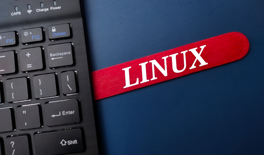Black keyboard and ice cream stick with the word LINUX on a blue background.