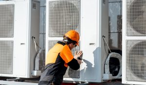 HVAC Professional in protective clothing installing or reparing outdoor unit of the air conditioner or heat pump on the rooftop