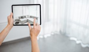 Placing new furniture on a digital tablet into the empty interior, looking how it looks before buying. Concept of augmented reality in design and retail business