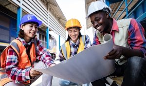 Construction managers working on train garage site and holding a blueprints project. Portrait of positive thinking of engineering teamwork. Happiness and successful concept