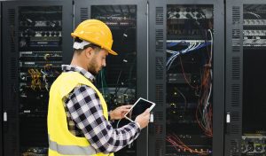 Young technician man working with tablet inside big data center room - Focus on right hand holding tablet