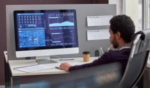 Back view at male IT engineer working with data on computer screen at workplace, copy space
