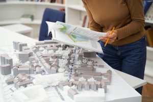 Unrecognizable female architect focused on designing architectural layouts at library desk