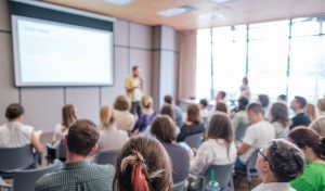 Group of people attending a presentation in a conference room. Speaker giving lecture to engaged audience.