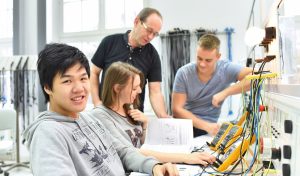 Instructor guiding trade school students through an electrical wiring lab exercise