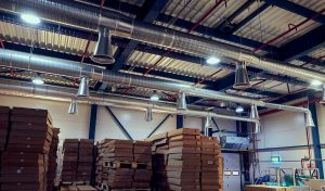 Warehouse ductwork and HVAC piping above stacked pallets of packaged goods