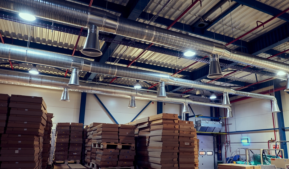 Warehouse ductwork and HVAC piping above stacked pallets of packaged goods