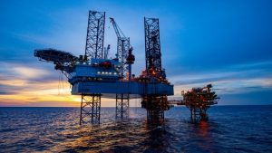 Offshore oil and gas platform operating in the ocean at sunset.