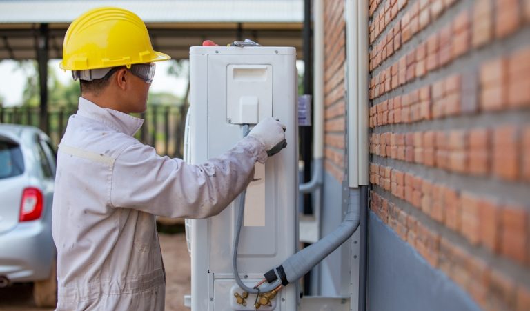 HVAC technician servicing an outdoor unit that uses A2L refrigerants